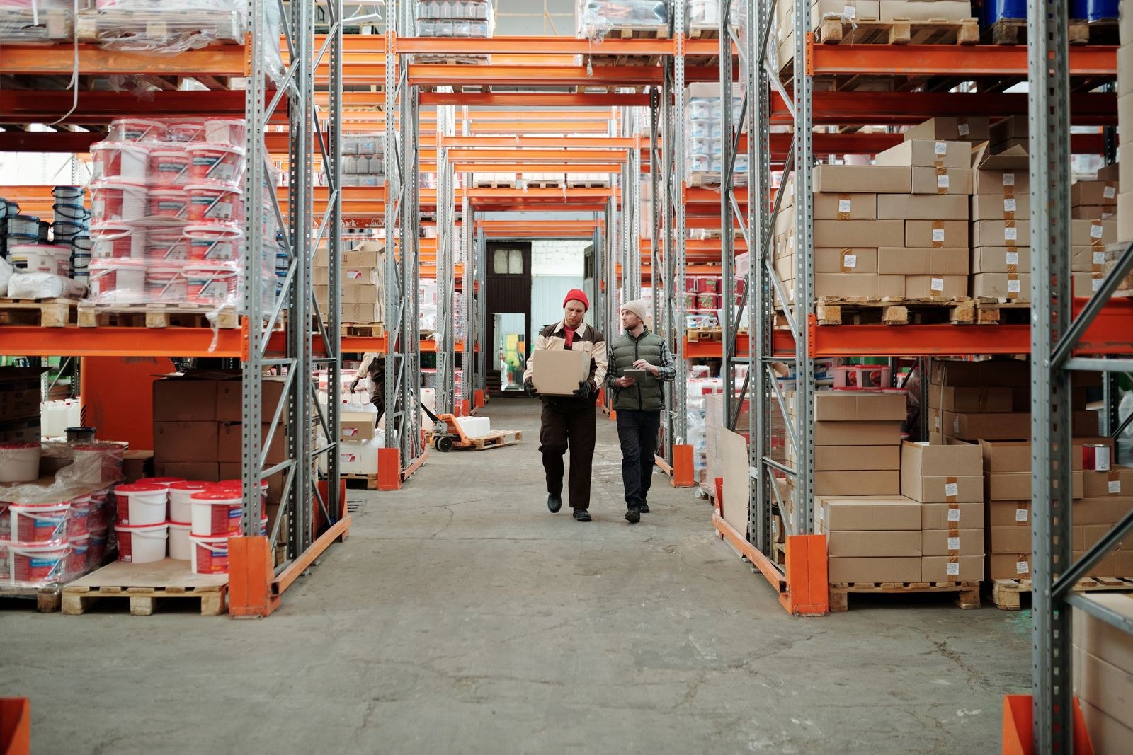 Warehouse aisle with racked materials and workers — waste reduction review at a small business